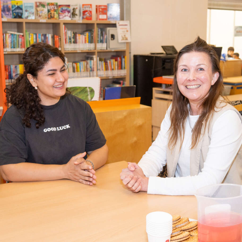 Brugfunctionaris Claudia in gesprek met een ouder in de schoolbibliotheek