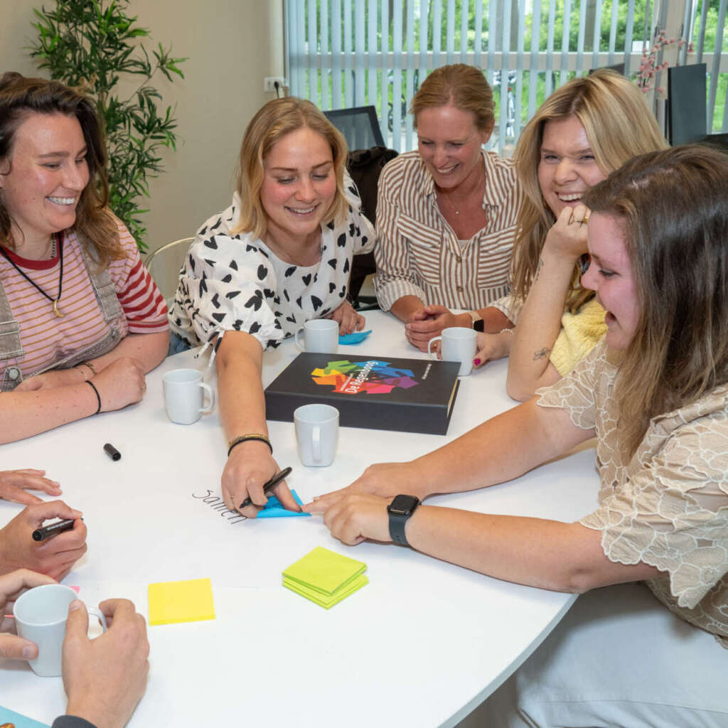 Teamleden van De Regenboog overleggen samen aan tafel