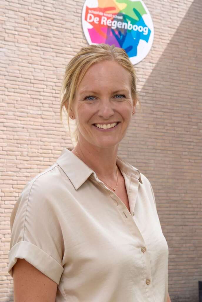 Anna Vreugdenhil, directeur van basisschool De Regenboog in Zoetermeer, voor de school bij het schoolbord aan de muur